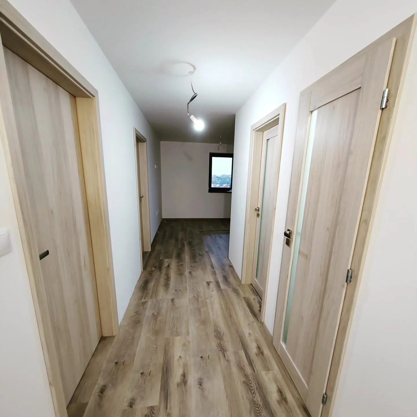 Chodba s dveřmi ve světlém dekoru dubu s prosklením